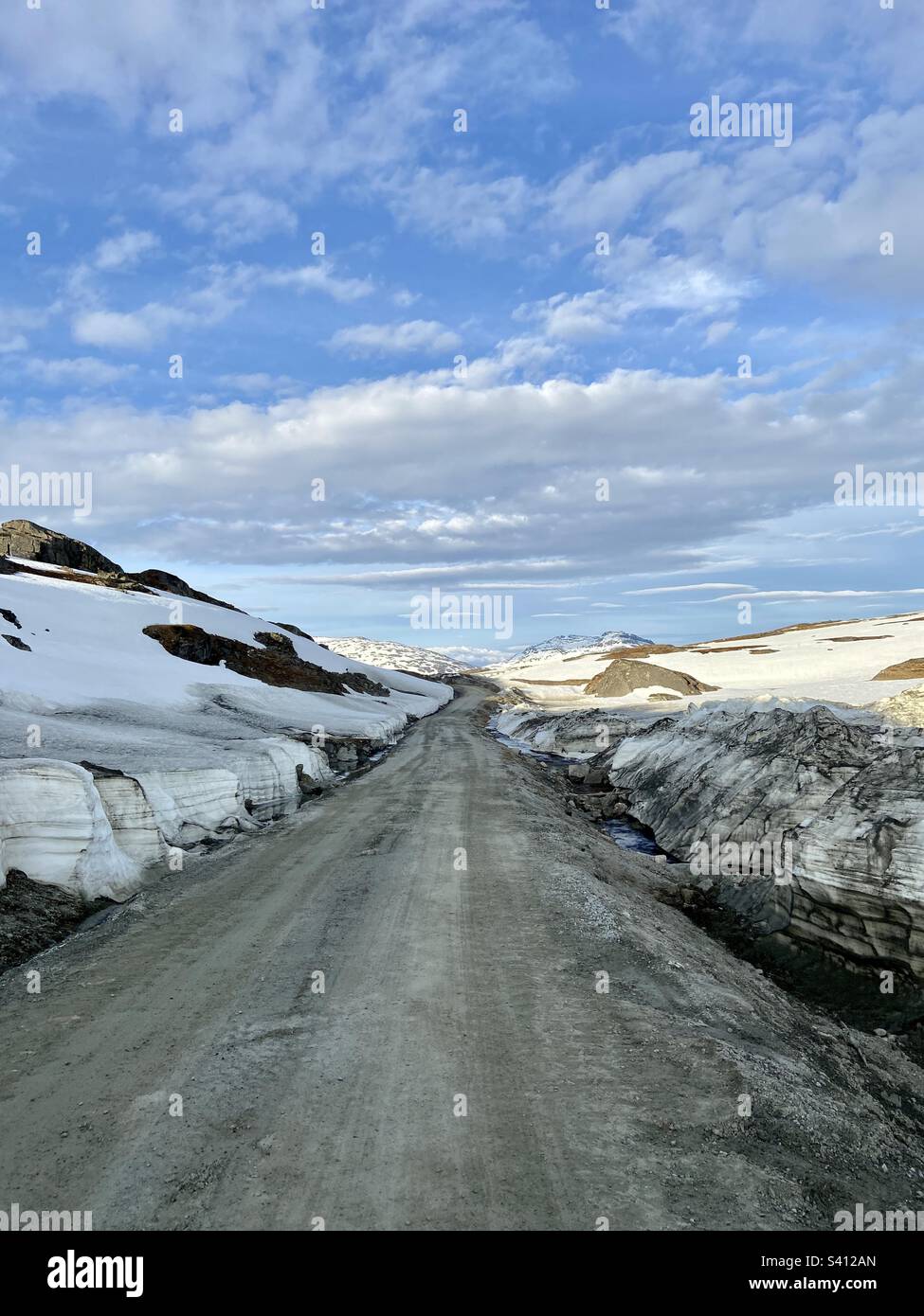 Guida su strada ghiaiata nella Norvegia settentrionale, in qualche punto più in alto di Fjelbu, vicino al confine con la Svezia. Ancora una partita di neve sciogliente nel mese di giugno, girato a tarda sera. - Immagine stock catturata con smartphone