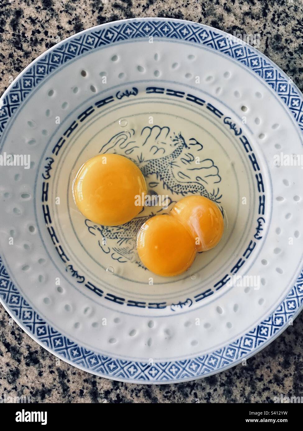 Un tuorlo e un uovo doppio su un piatto Foto Stock