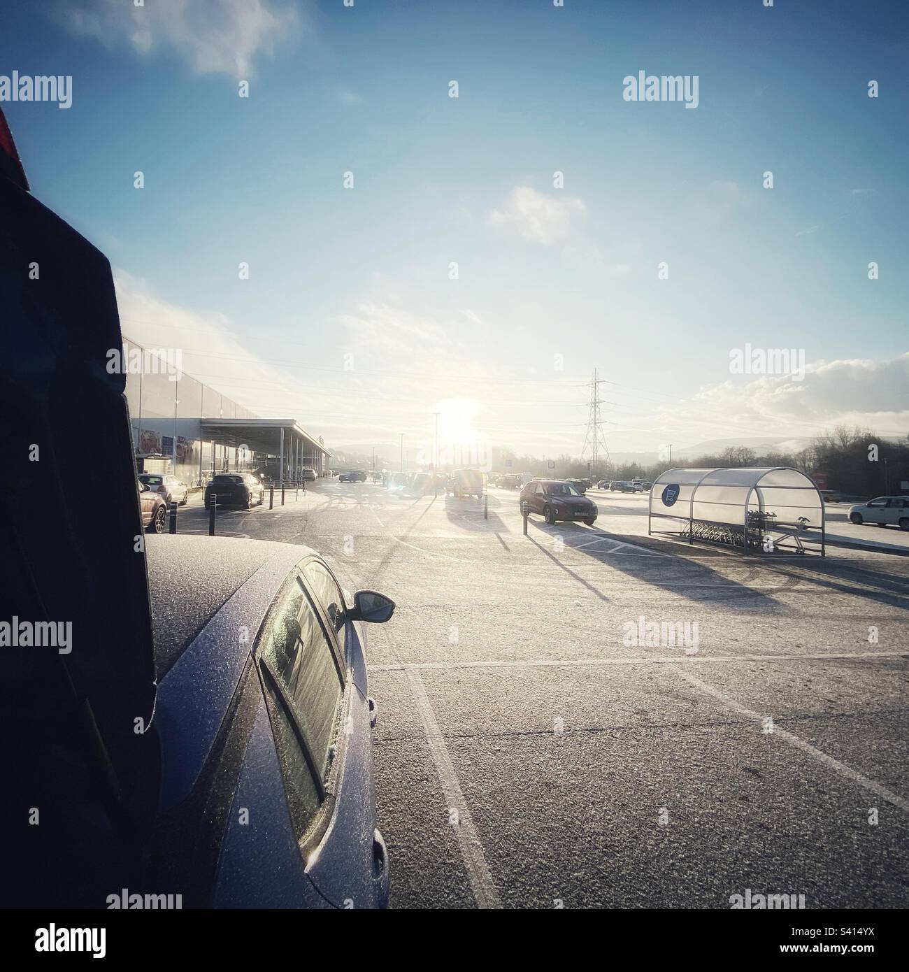 Una fotografia di un parcheggio da supermercato innevato in una fredda giornata invernale. Shopping al dettaglio in cattive condizioni atmosferiche. Foto Stock