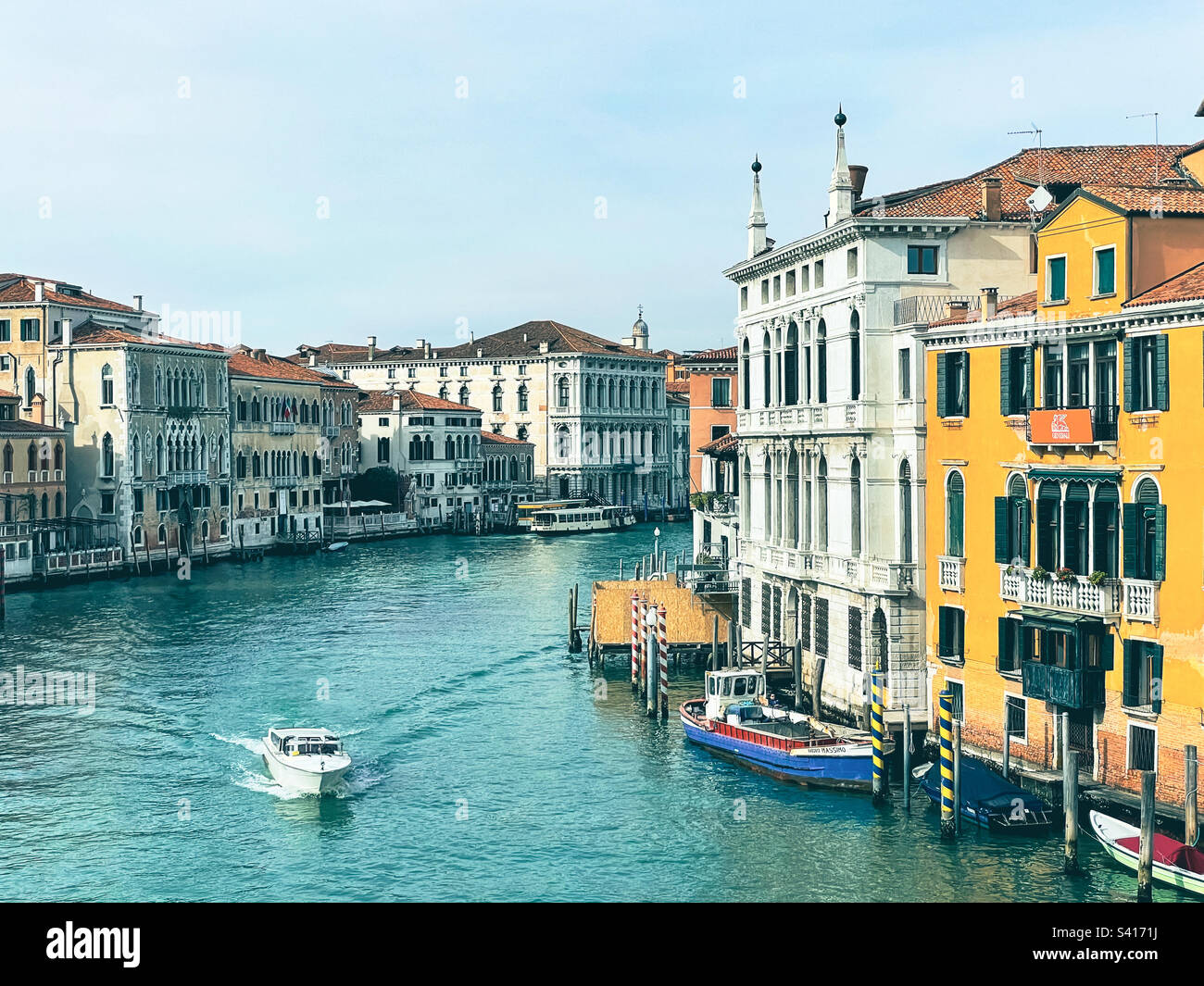 Vista del Canal grande e dei suoi palazzi a Venezia dal Ponte dell'Accademia in una soleggiata giornata invernale con una piccola barca che si muove in acqua - Immagine stock catturata con smartphone