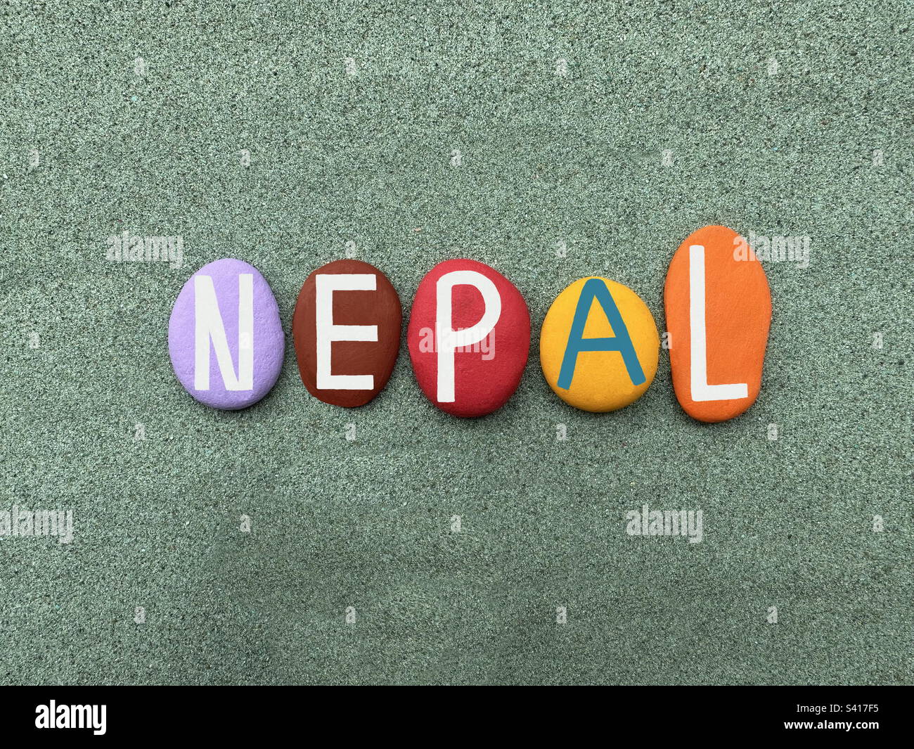 Nepal, paese senza sbocco sul mare in Asia meridionale, souvenir composto da lettere in pietra multicolore dipinte a mano su sabbia verde - Immagine stock catturata con smartphone