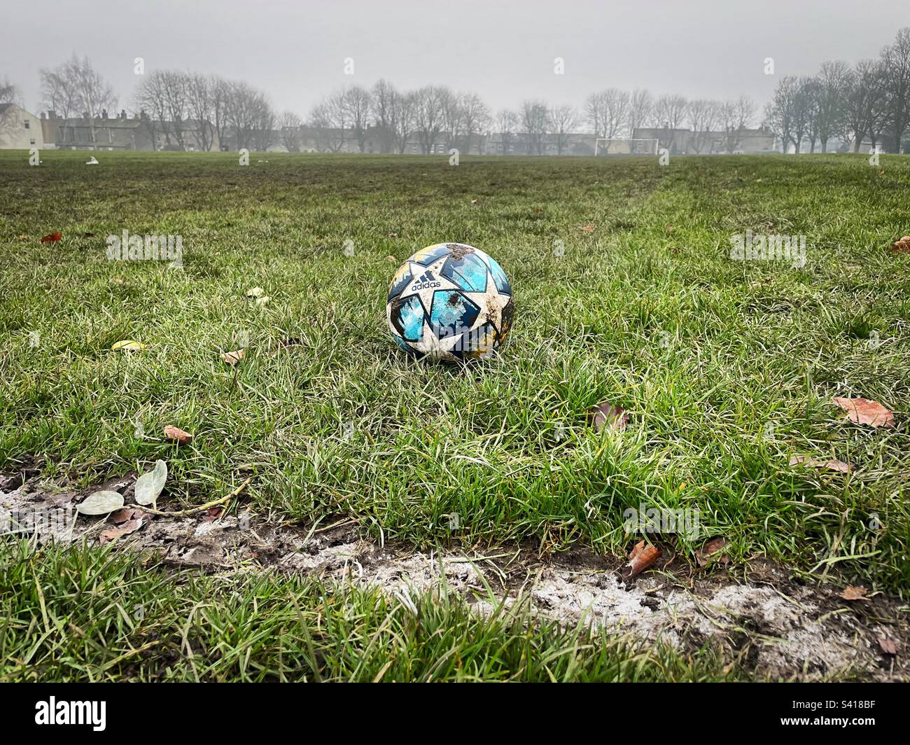 ‘Grassroots’ un calcio siede vicino alla linea di contatto su un terreno fangoso e troppo cresciuto locale. Foto Stock