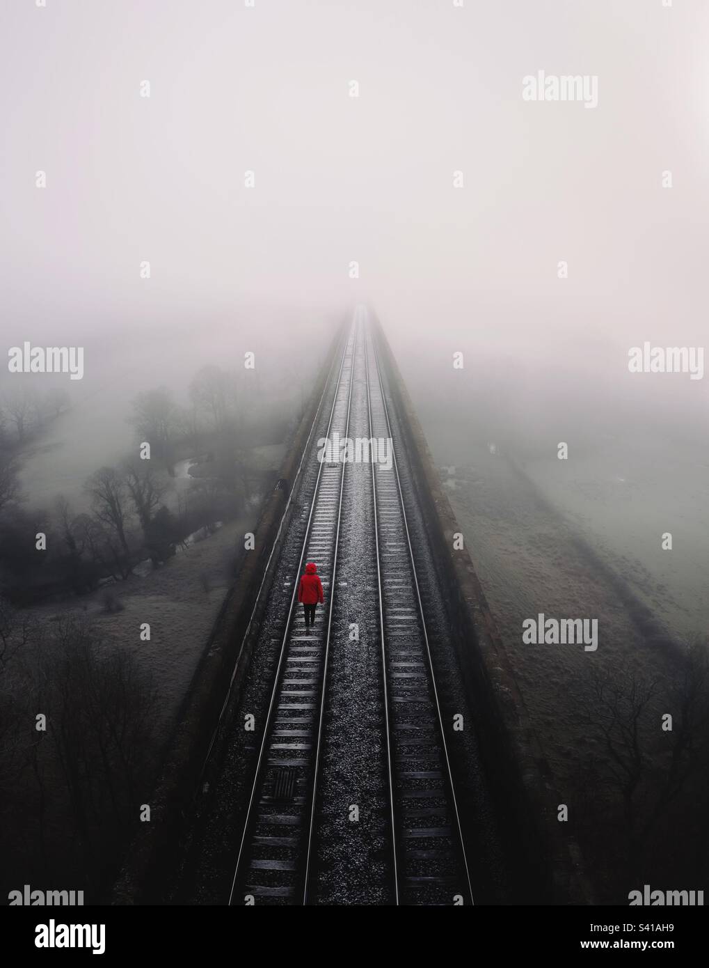 Un'anima perduta che cammina nell'oblio su una linea ferroviaria in un concetto suicida o di depressione Foto Stock