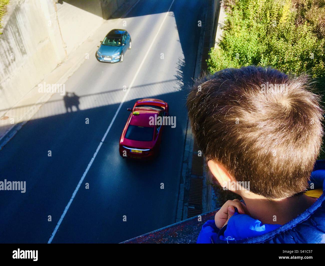 Bambino ragazzo che guarda giù dal ponte sulle auto - Immagine stock catturata con smartphone Bambino ragazzo che guarda giù dal ponte sulle auto - Immagine stock catturata con smartphone