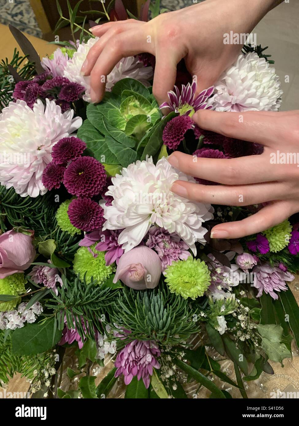 Mani femminili che organizzano i fiori in un bouquet Foto Stock