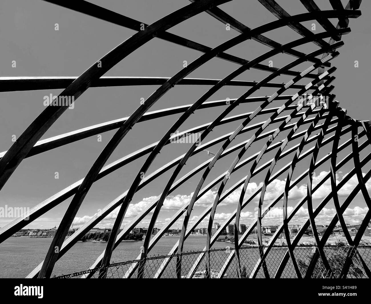 Foto monocromatiche in bianco e nero con vista del cielo e del mare attraverso le moderne celle rombiche dell'edificio a gabbia Foto Stock