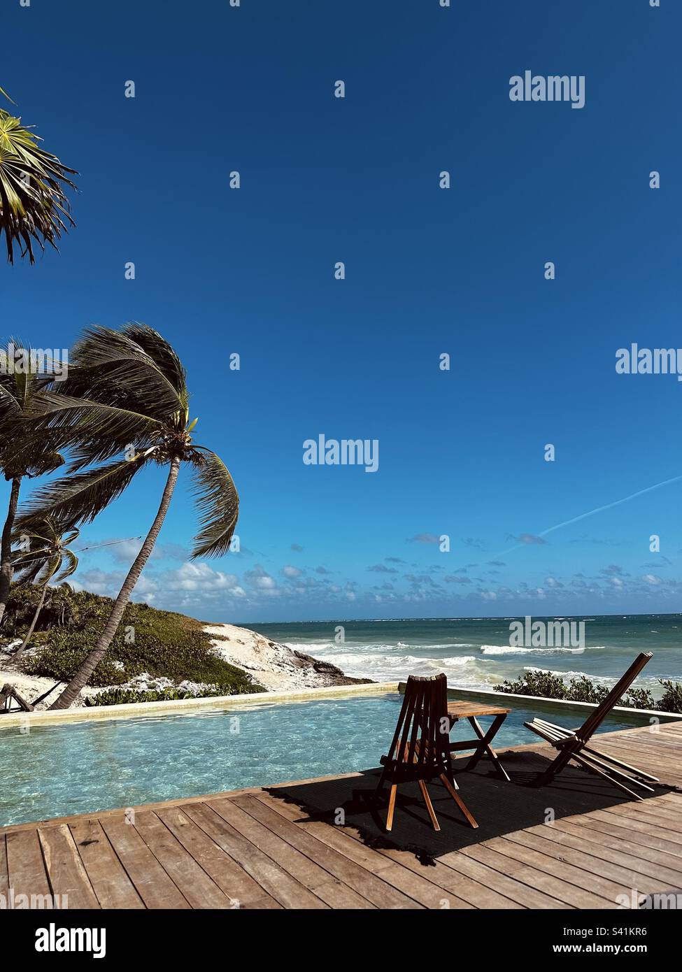 Palme, piscina, sedia e tavolino da caffè a Tulum Beach, Tulum, Messico, con vista sul Mar dei Caraibi - Immagine stock catturata con smartphone