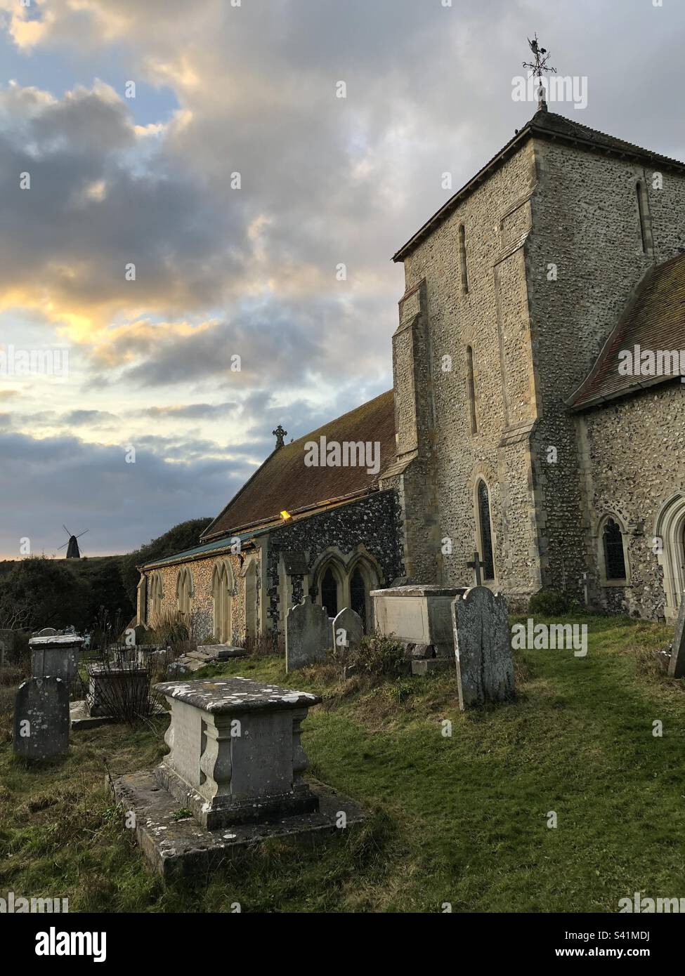 Chiesa di Santa Margherita con Beacon Mill sulla cima della collina sullo sfondo a Rottingdean, Sussex occidentale, Inghilterra. Foto Stock