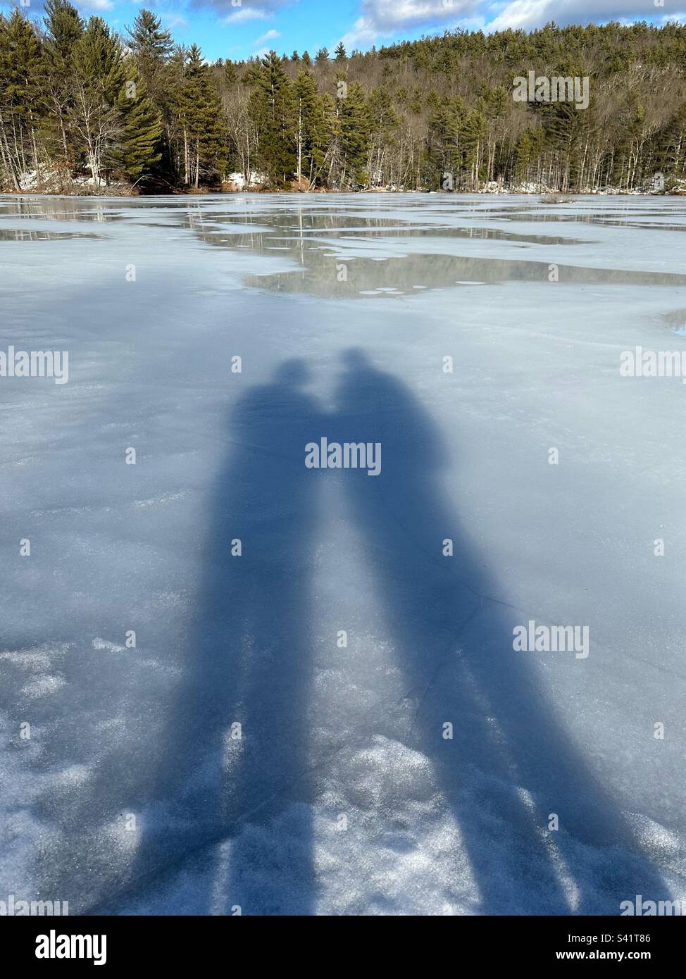 Lunghe ombre di due persone sul ghiaccio bianco del lago ghiacciato in inverno - Immagine stock catturata con smartphone