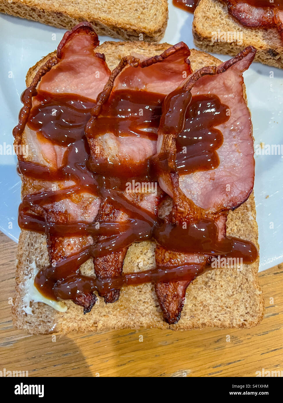 Sandwich con pancetta su pane integrale con salsa di colore marrone Foto Stock