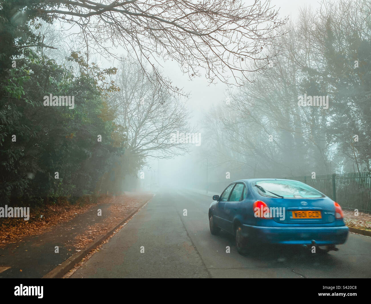 Auto che guida lungo una strada su una mattina nebbiosa e nebbia. Foto Stock