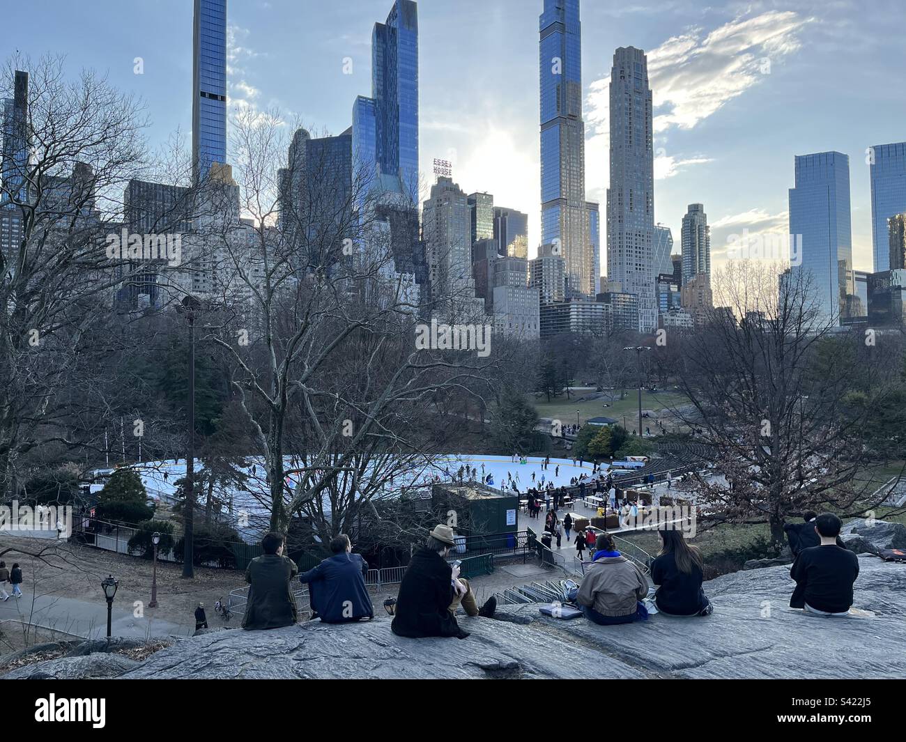 Tramonto dietro l'Essex House e lo skyline di New York. Vista sulla pista di Wollman a Central Park, New York, Stati Uniti. Febbraio 20, 2023. Foto Stock