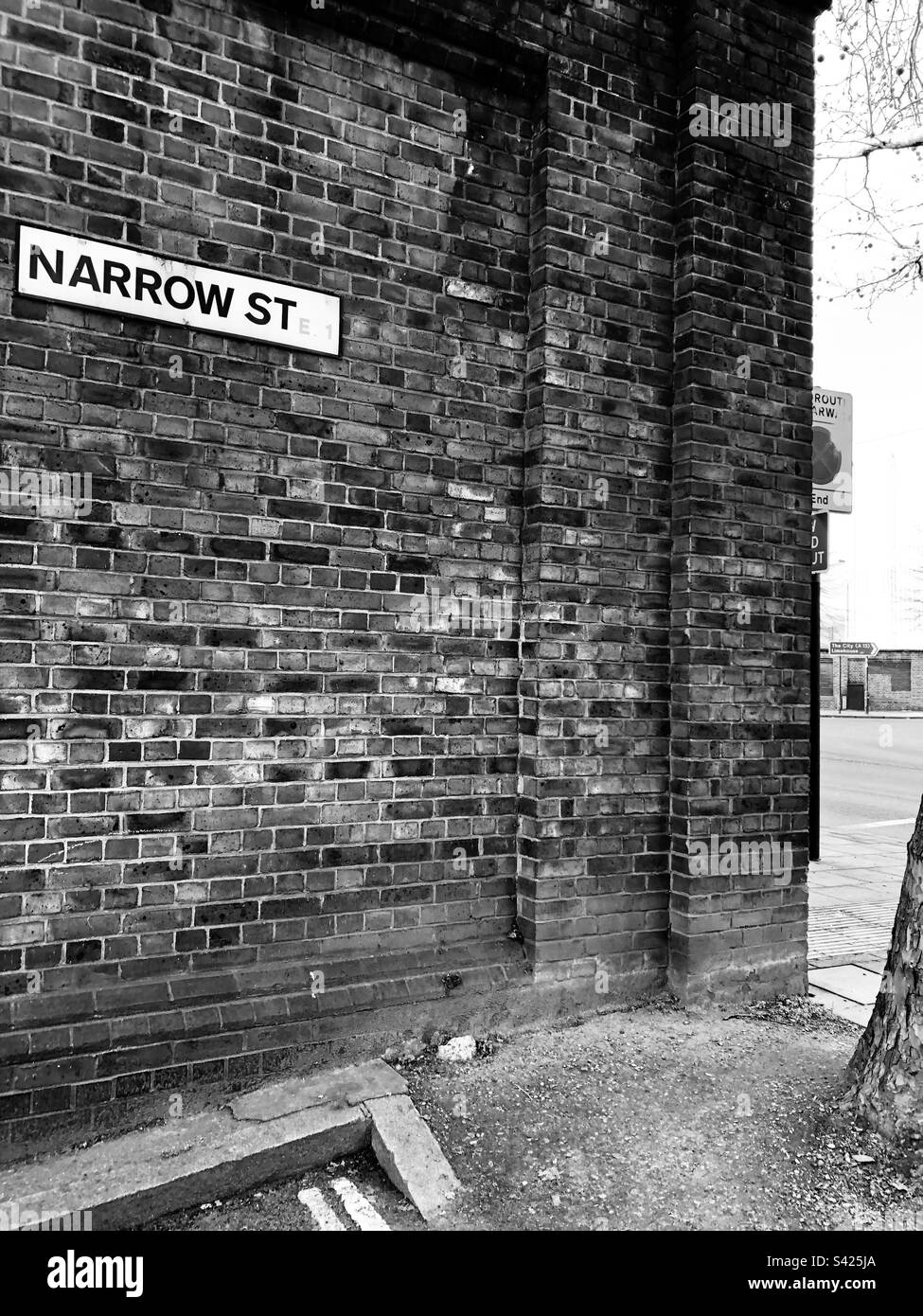 Cartello Narrow Street sulla parete di mattoni Wapping London B&W. Foto Stock
