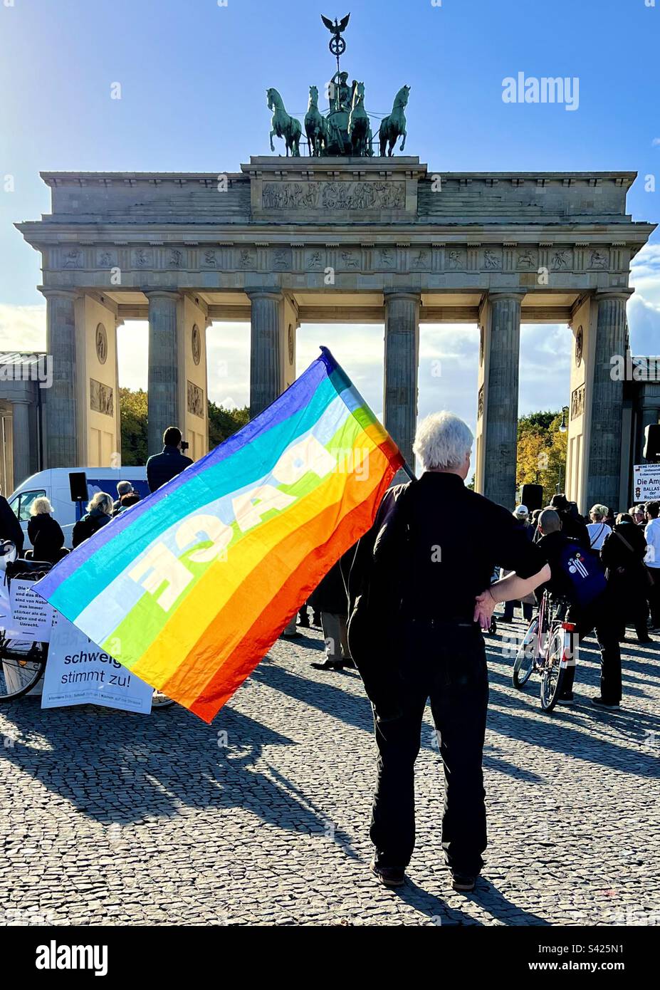 Bandiera della pace arcobaleno e donna alla porta di Brandeburgo, Mitte, Berlino, Germania Foto Stock
