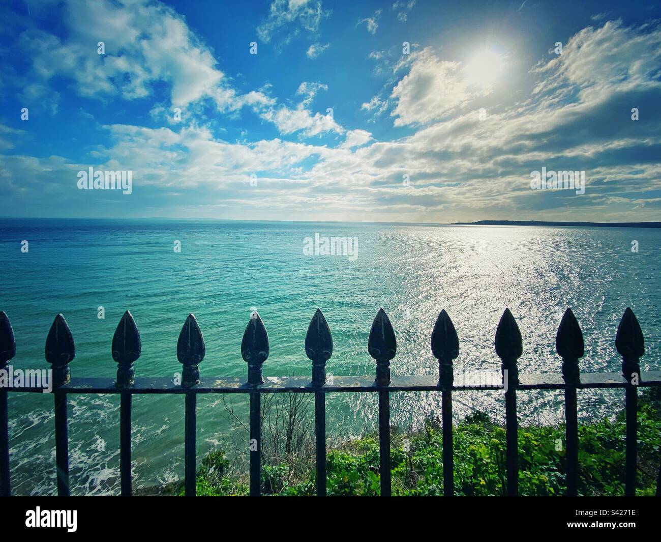 Una fotografia dell'oceano dal lungomare di Tenby. Ringhiere in primo piano con splendida vista mare turchese. Foto Stock