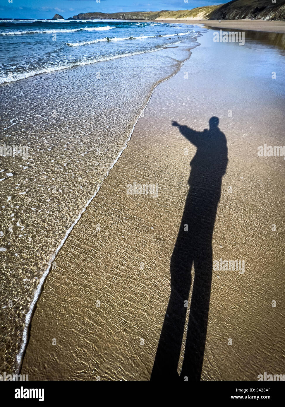 Ombra dell'uomo che indica il mare, Perranporth Beach, Cornovaglia, Regno Unito. - Immagine stock catturata con smartphone