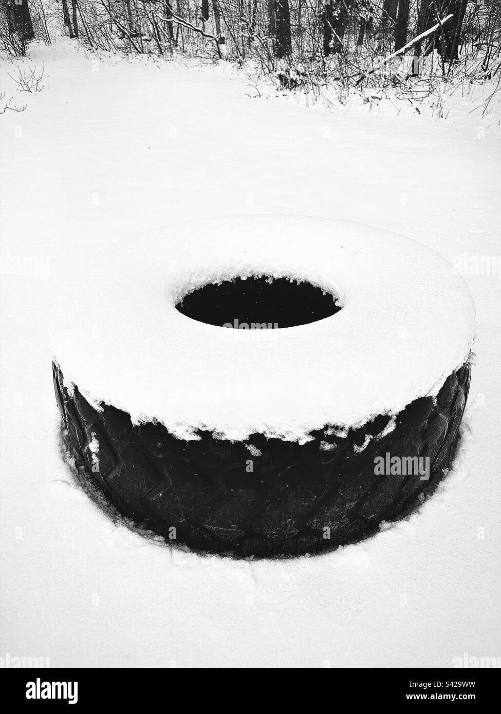 Grande pneumatico coperto di neve dopo la recente tempesta di neve in New England. Alberi sullo sfondo. Filtro Hipstamatic. - Immagine stock catturata con smartphone