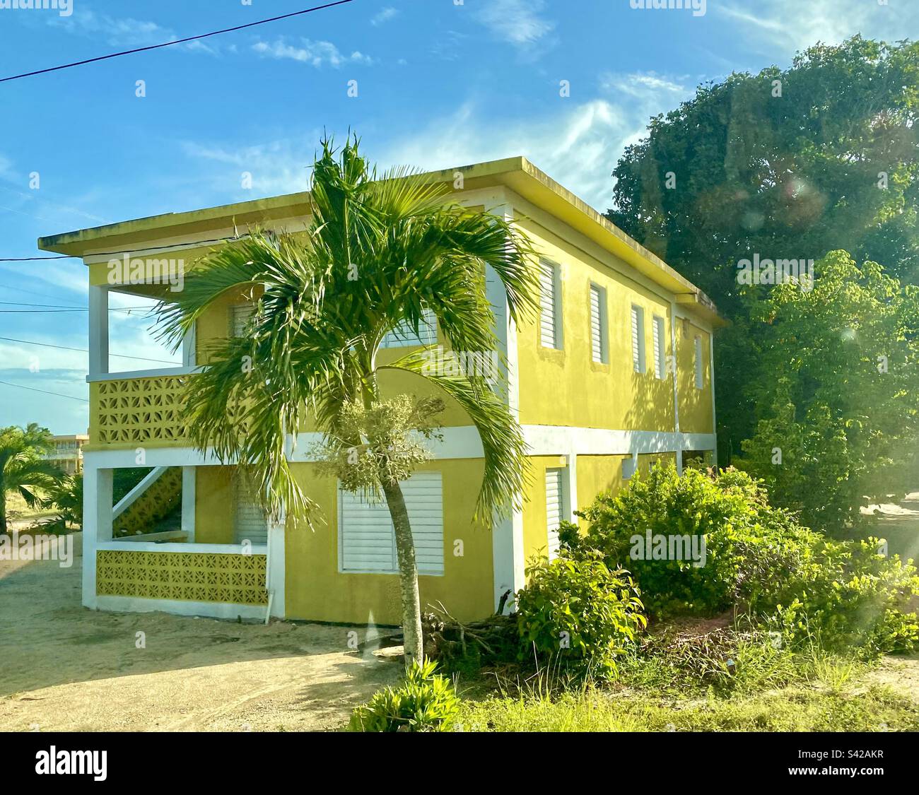 La casa rettangolare di colore giallo dorato si distingue contro il cielo azzurro di Hopkins, Belize - Immagine stock catturata con smartphone
