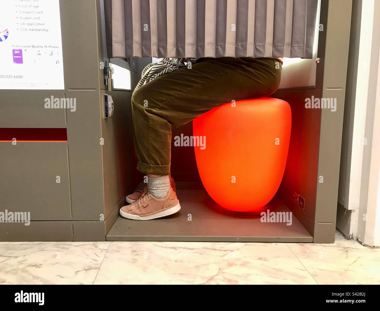 Cliente Feale che utilizza una macchina per cabina fotografica nel Regno Unito Foto Stock