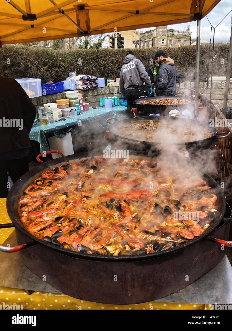 Primo piano vapore che sale da Paella Pan Cooking Seafood Paella Street food spagnolo al mercato agricolo locale nel Regno Unito - Immagine stock catturata con smartphone