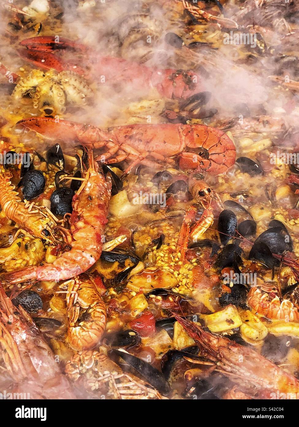 Primo piano vapore che sale da Paella Pan Cooking Seafood Paella Street food spagnolo al mercato agricolo locale nel Regno Unito - Immagine stock catturata con smartphone