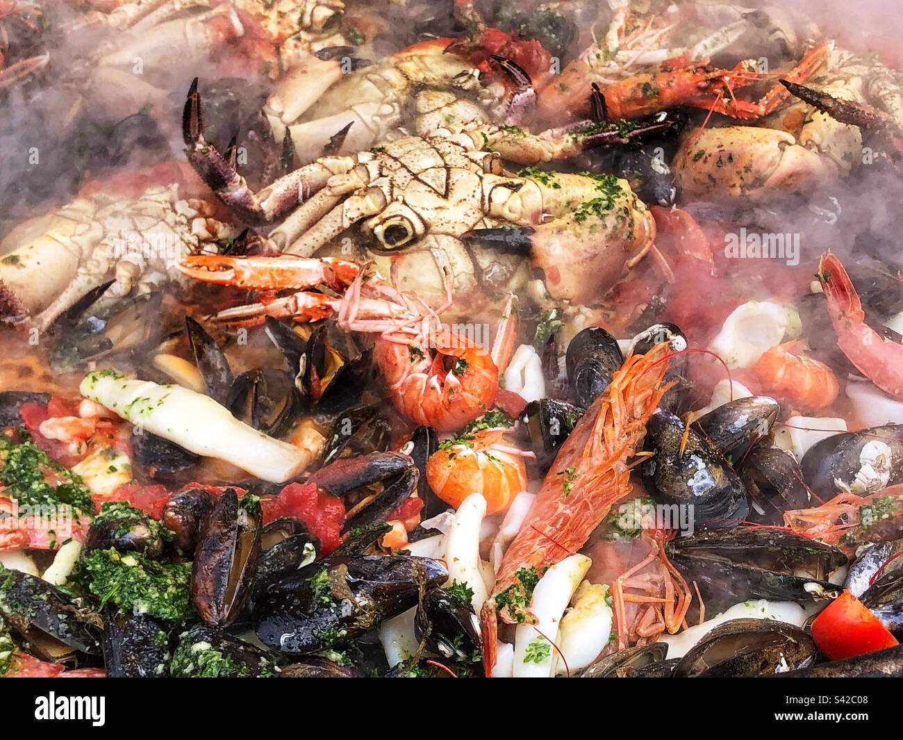 Primo piano vapore che sale da Paella Pan Cooking Seafood Paella Street food spagnolo al mercato agricolo locale nel Regno Unito - Immagine stock catturata con smartphone