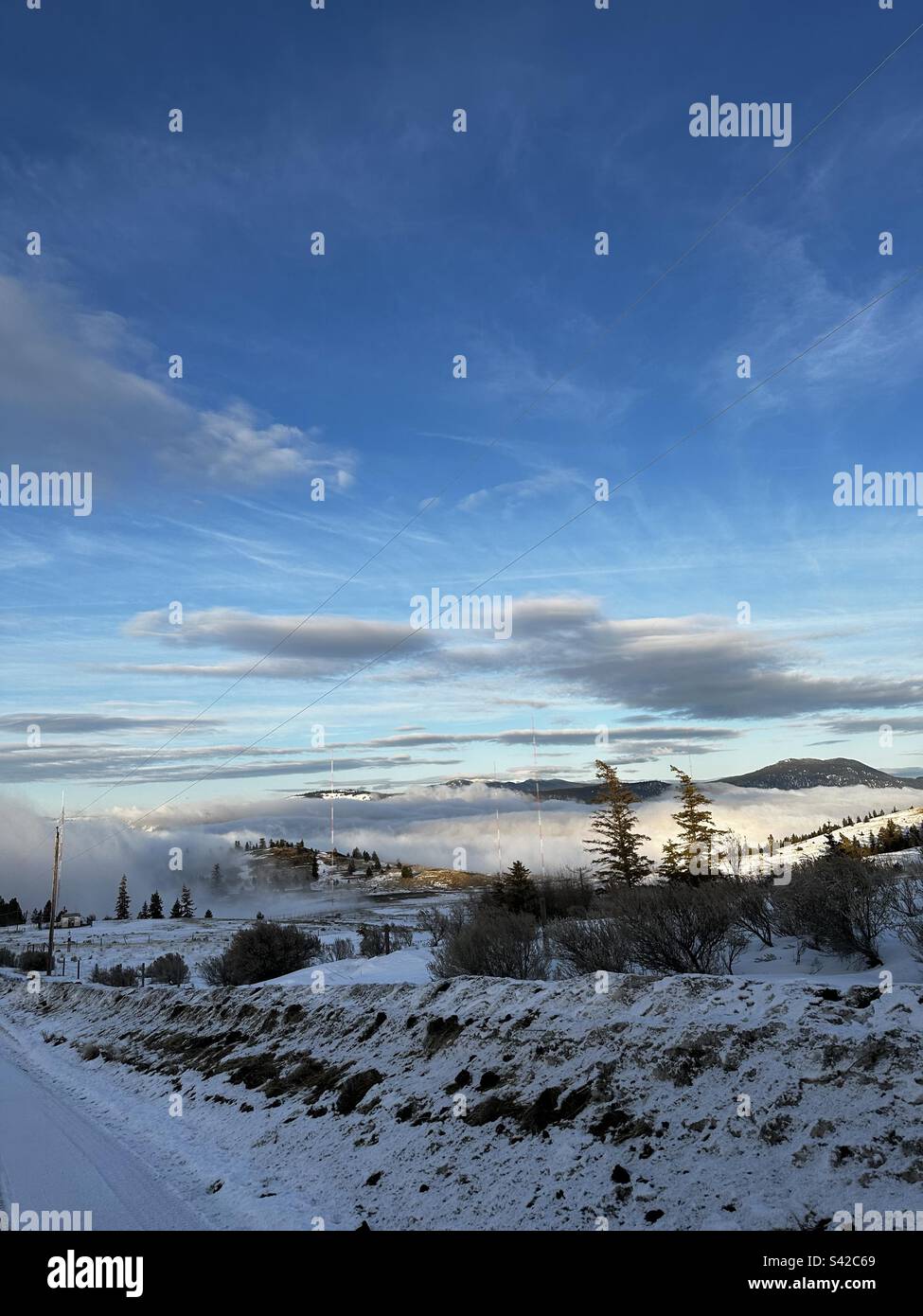 Una coperta di nuvole circonda le montagne di Kamloops, BC con cielo blu sopra Foto Stock