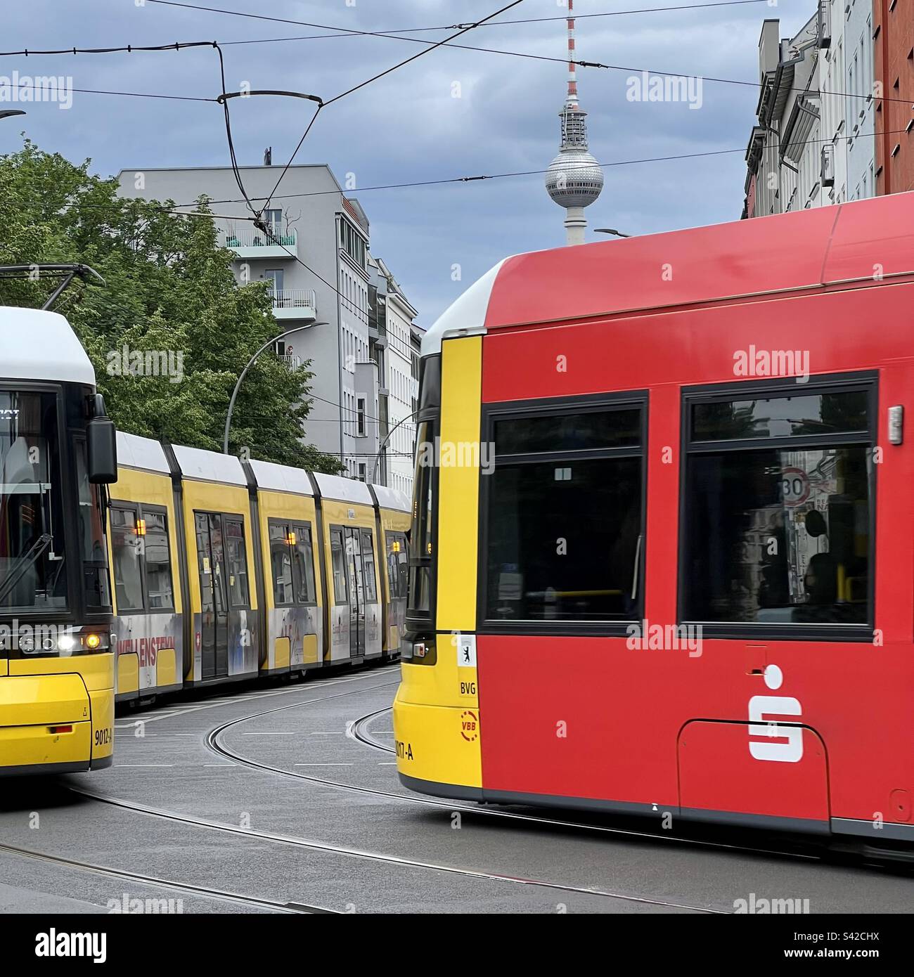 Due tram sulla strada della città con la torre della televisione sullo sfondo, Mitte, Berlino, Germania. Trasporti pubblici Foto Stock