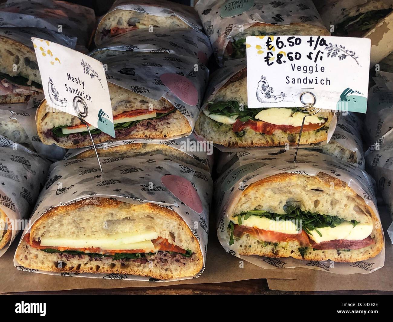 Sandwich di carne appena fatti e panino vegetariano in vendita nella vetrina del caffè - Immagine stock catturata con smartphone