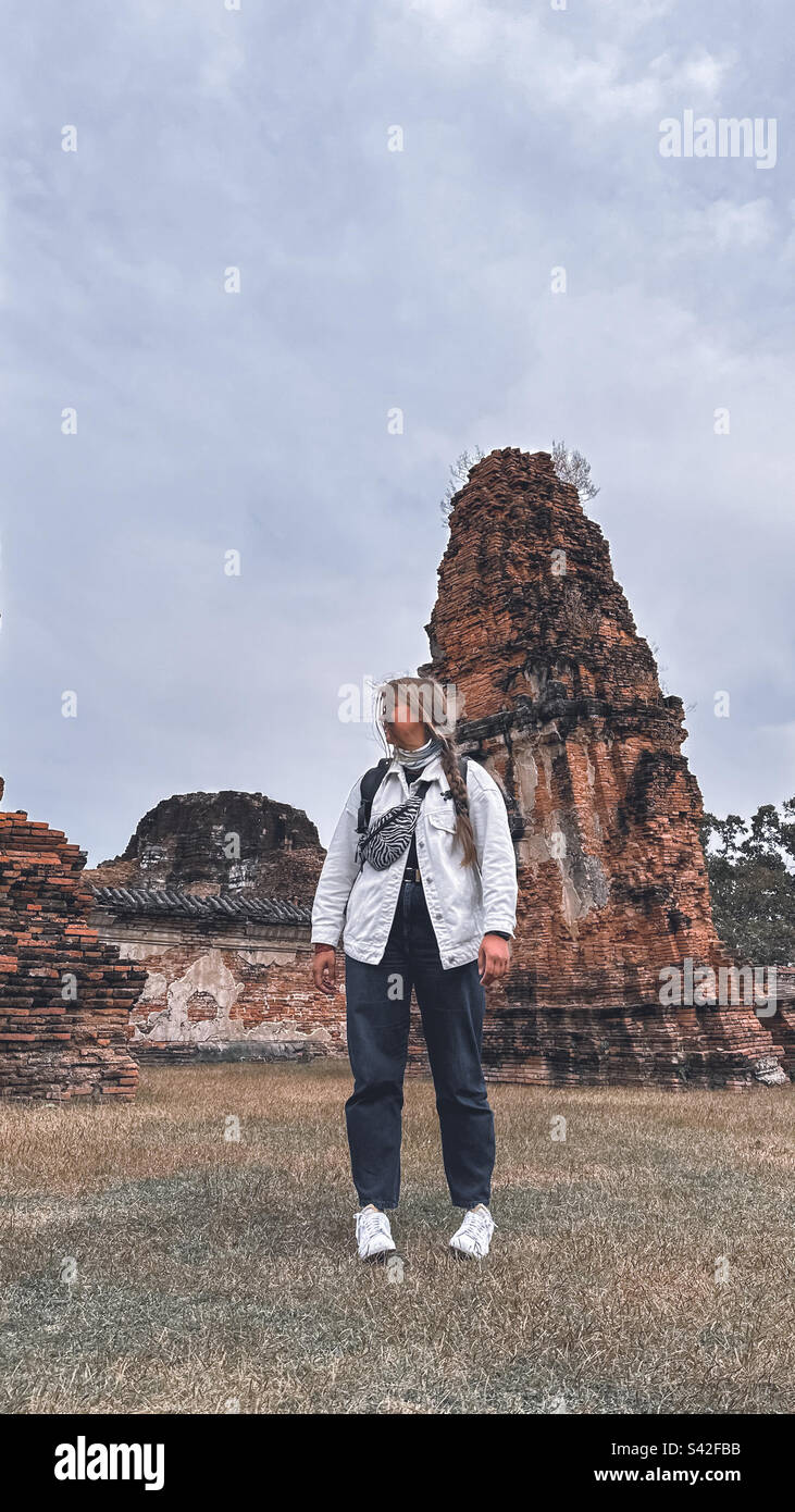 Una giovane donna in piedi di fronte a un antico stupa buddista in Ayutthaya Foto Stock