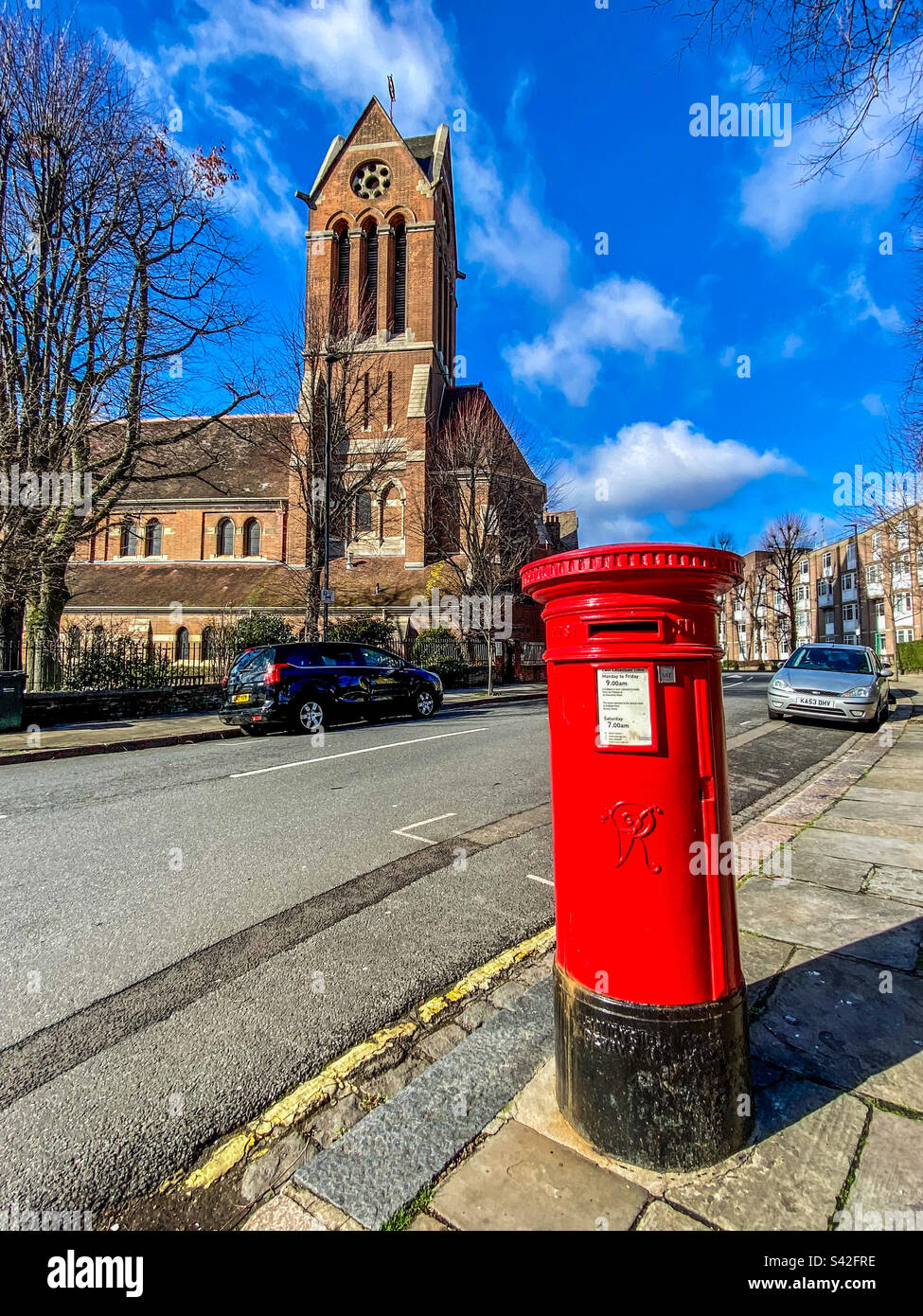 Una casella postale rossa e una chiesa in una giornata di sole a Londra - Immagine stock catturata con smartphone