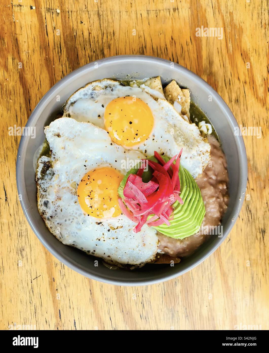 Peperoncini con salsa habernos verde, fagioli fritti, uova condite, avocado e cipolle sottaceto. Foto Stock
