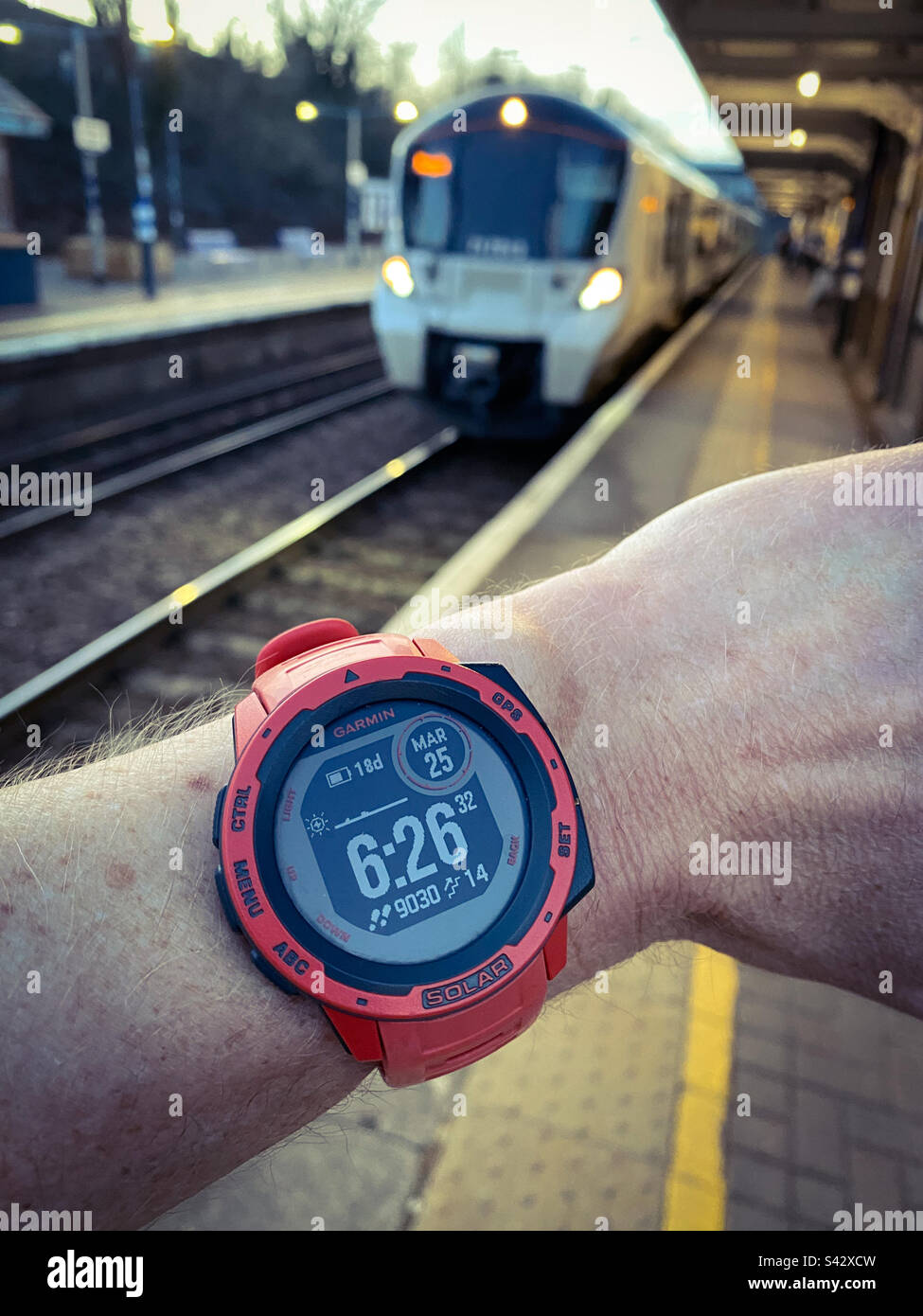 Un uomo controlla l'ora mentre un treno arriva ad una stazione a Londra in Inghilterra Foto Stock