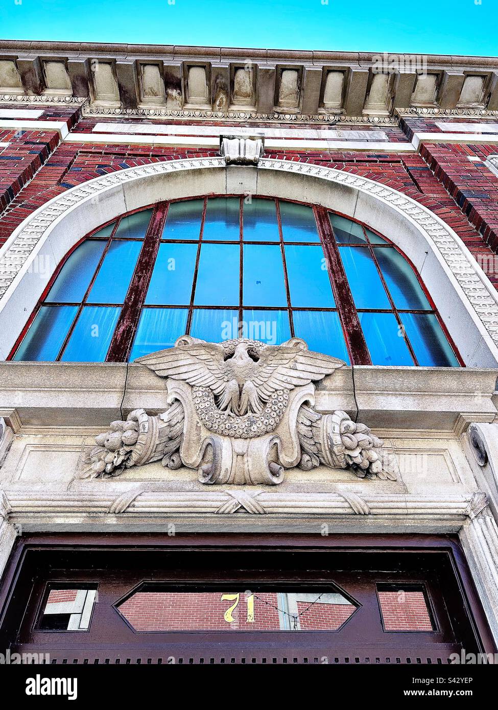 Si affaccia sopra la porta del vecchio edificio a Norwich, Connecticut, nel centro città. Architettura in mattoni rossi con arco e finestra. Con scultura in pietra di aquila e simboli del raccolto. Foto Stock