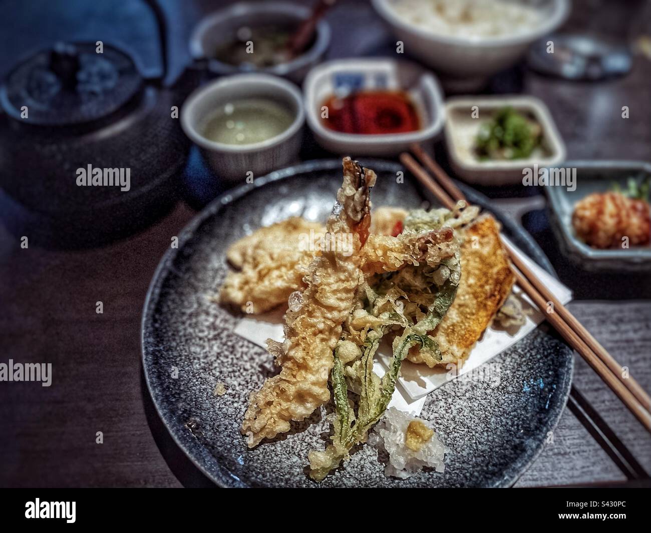 Tempura mista su piatto con riso, tè verde in tazza, teiera e condimenti giapponesi sul tavolo. - Immagine stock catturata con smartphone