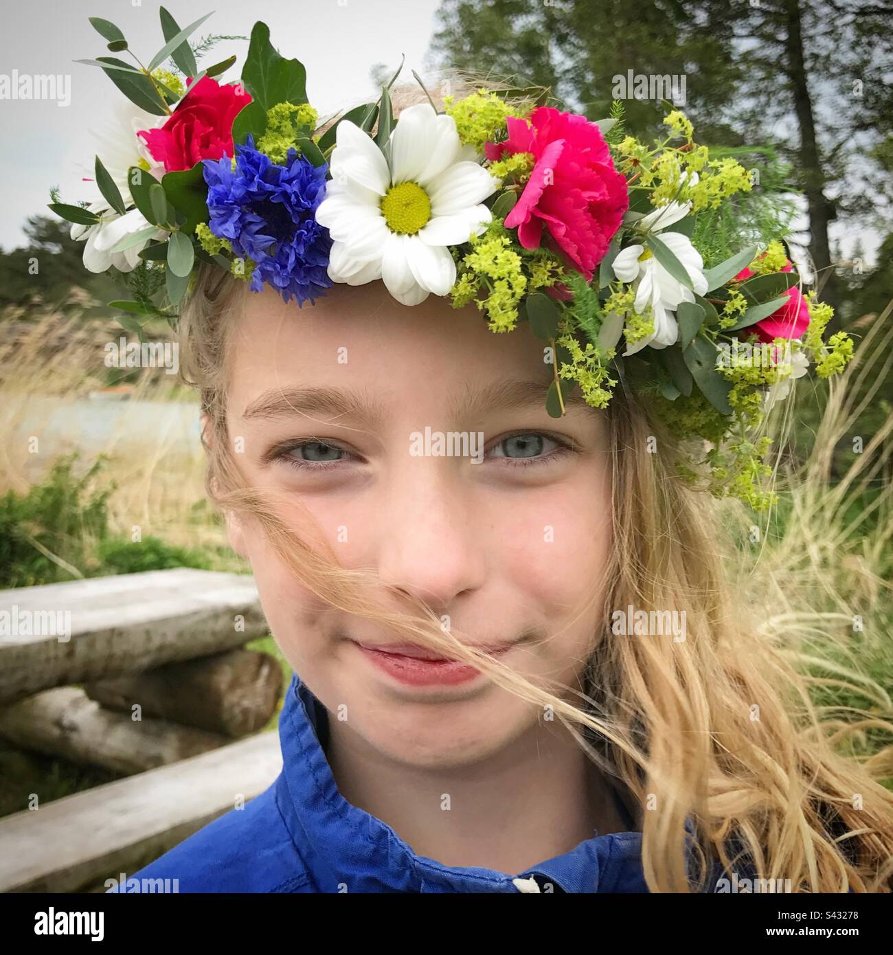 Giovane nordica ragazza scandinava in una tradizionale corona floreale di fiori (conosciuta come corona di corona o cappelletto) indossata durante la festa di mezza estate Foto Stock