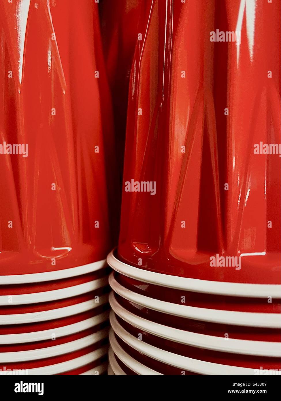 Due pile lucide di tazze in plastica rosse del marchio solo riempiono l'intera struttura. Foto Stock