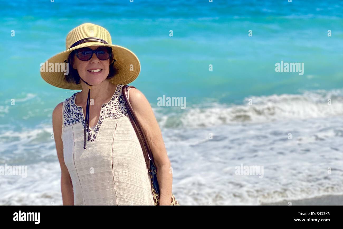 Ritratto di una donna che cammina lungo la spiaggia con l'oceano dietro di lei. Foto Stock