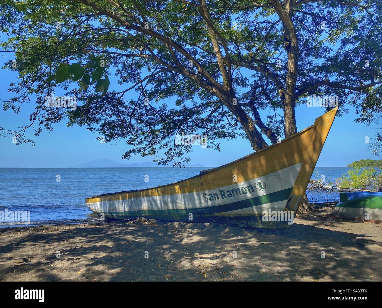Bianco giallo e blu Barca da pesca all'ombra di un treeon Ometepe Isola Nicaragua - Immagine stock catturata con smartphone