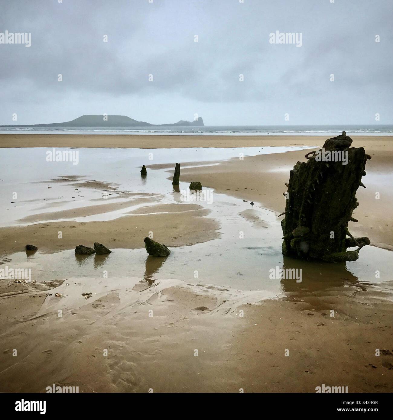 Il naufragio della Helvetia sulla splendida spiaggia di Rhossili sulla costa di Gower del Galles occidentale in una tempesta con Worms Head sullo sfondo Foto Stock