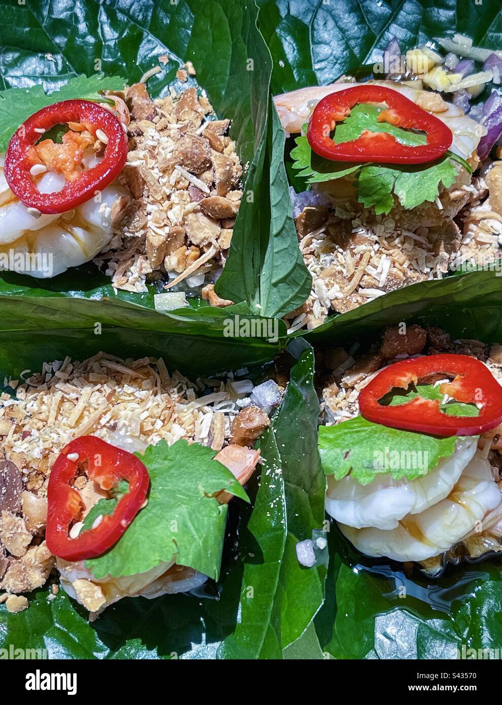 Vista ad angolo alto di quattro legnature di foglie di betel di gamberi, miang khan, popolare cibo di strada tailandese. - Immagine stock catturata con smartphone