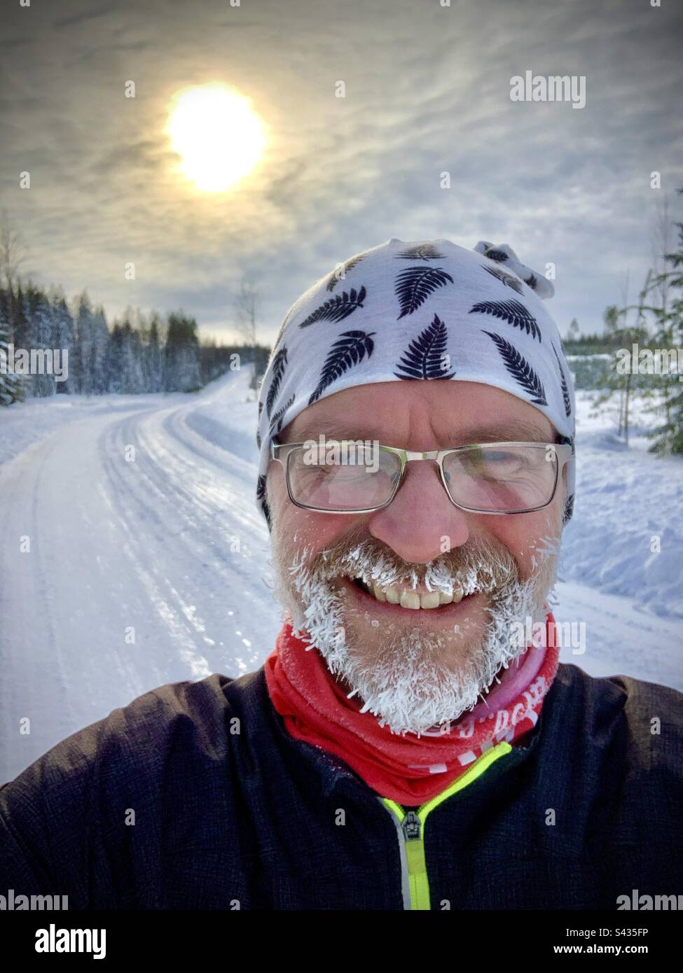 Un selfie divertente di un uomo di mezza età con una barba di ghiaccio dopo aver corso nel freddo estremo delle profondità di un inverno ghiacciato nella regione del Circolo polare Artico in Finlandia Foto Stock