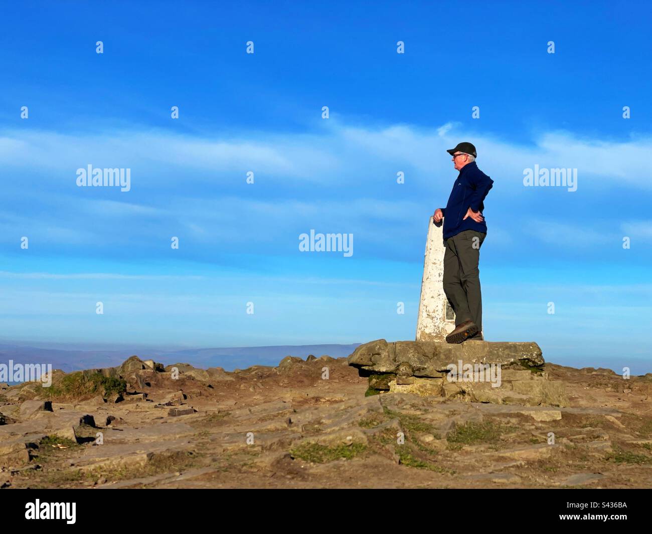 Uomo che si trova vicino al punto di trig della cima del monte Sugarloaf, Abergavenny, Brecon Beacons, Galles. - Immagine stock catturata con smartphone