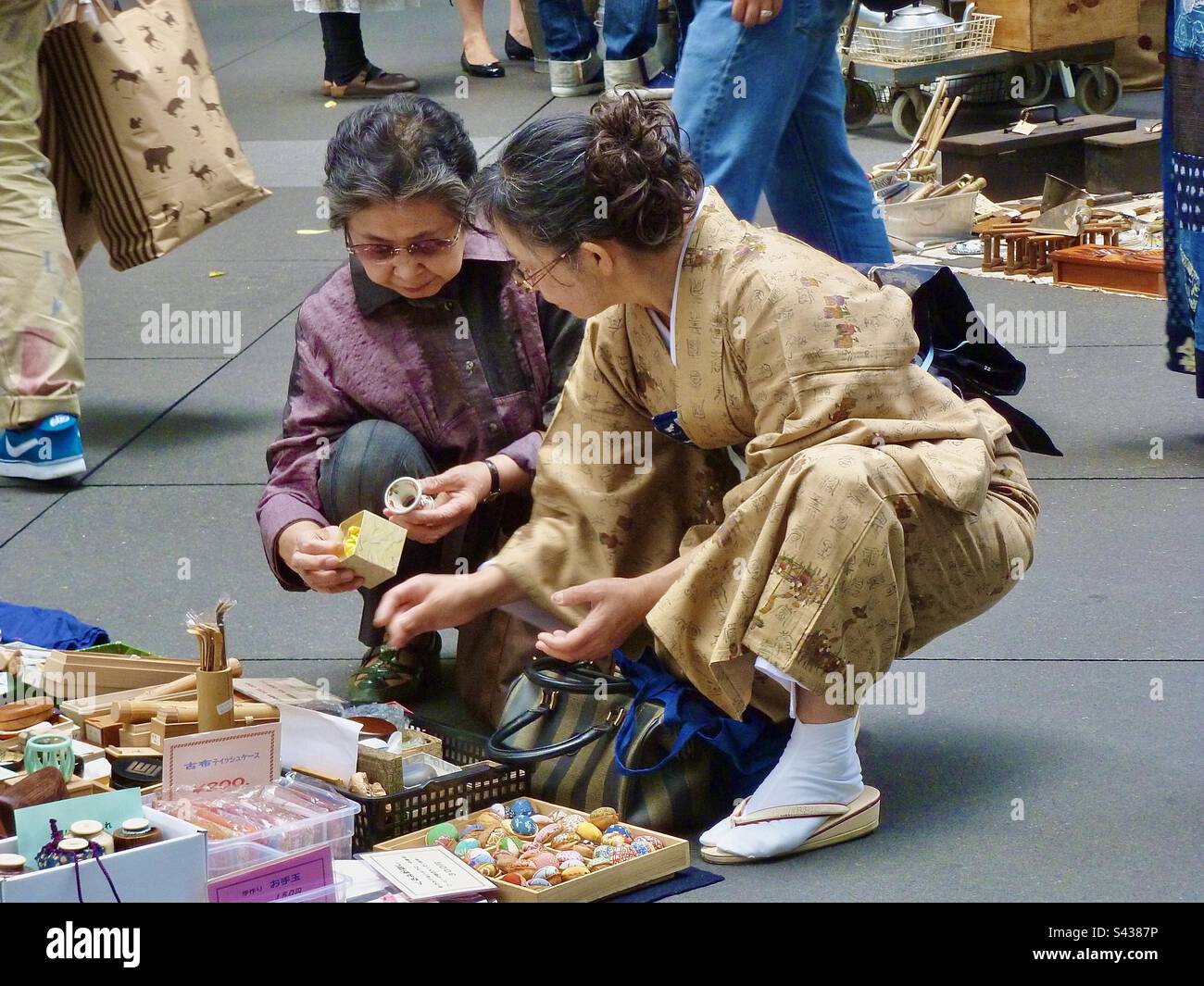 Le donne giapponesi si accovacciano per guardare gli oggetti del mercato di stallo nel mercato di strada di Tokyo in Giappone Foto Stock