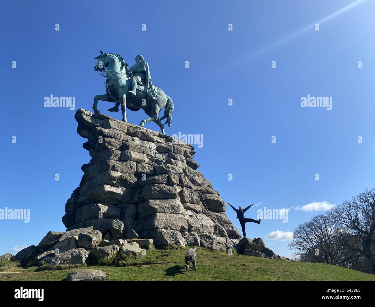 Una persona si posa per una fotografia in piedi accanto alla statua di Giorgio III sul suo cavallo di rame nel Windsor Great Park in Inghilterra. Foto Stock