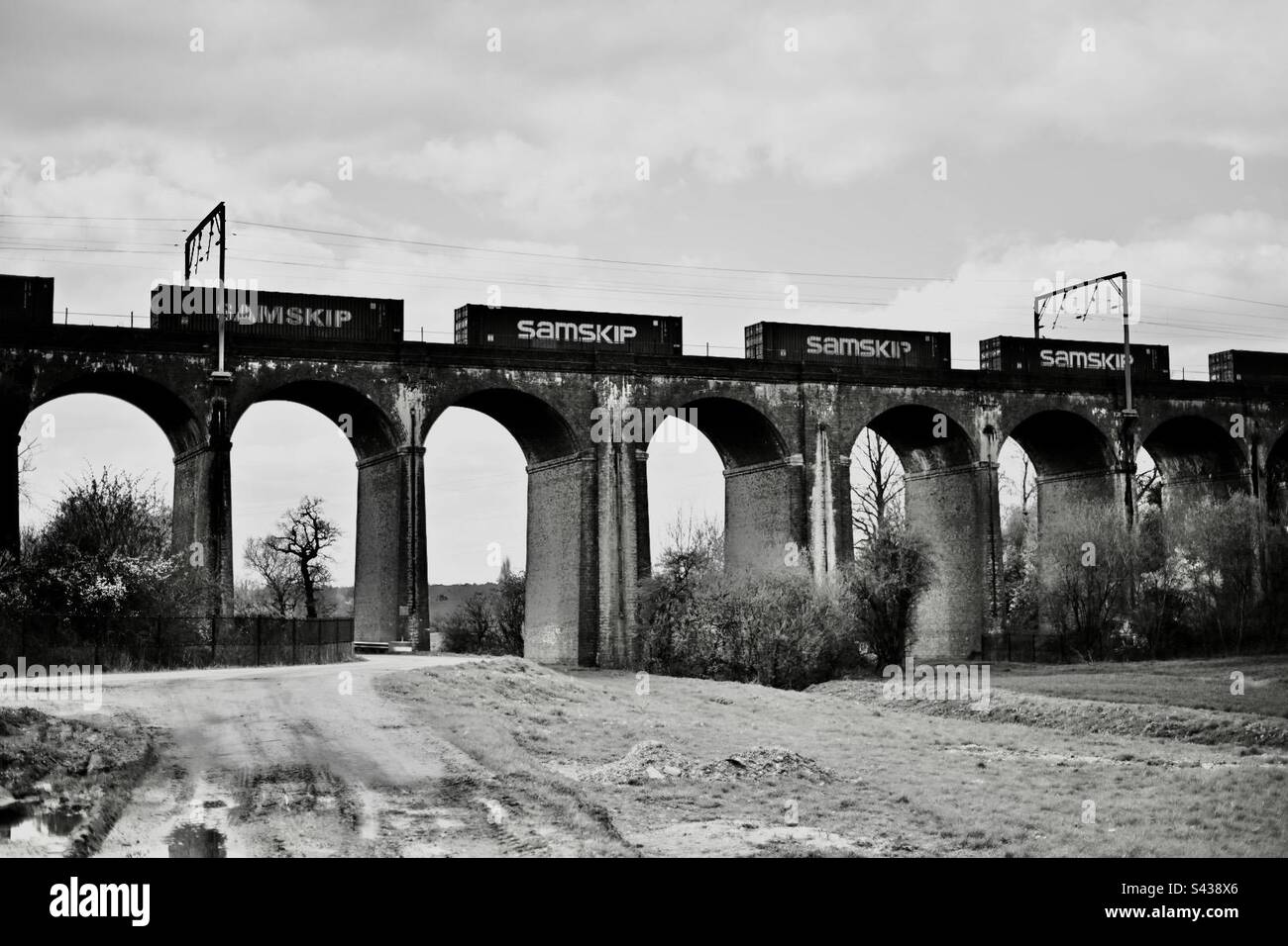 Un treno merci passa su un ponte ferroviario costruito in mattoni a nord di Londra - Immagine stock catturata con smartphone