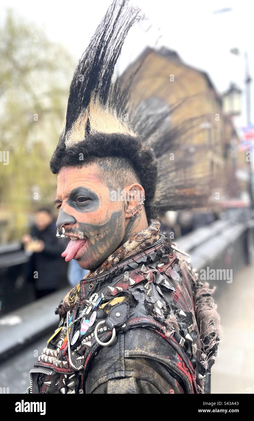 Un uomo punk colorato con una lingua biforcuta e un'acconciatura Mohawk nel mercato di Camden a Londra, Regno Unito. - Immagine stock catturata con smartphone