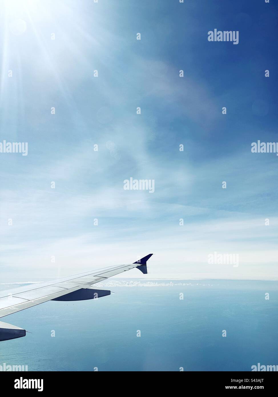 Sole che splende sull'oceano blu, sull'ala dell'aeroplano e sul cielo. Foto Stock