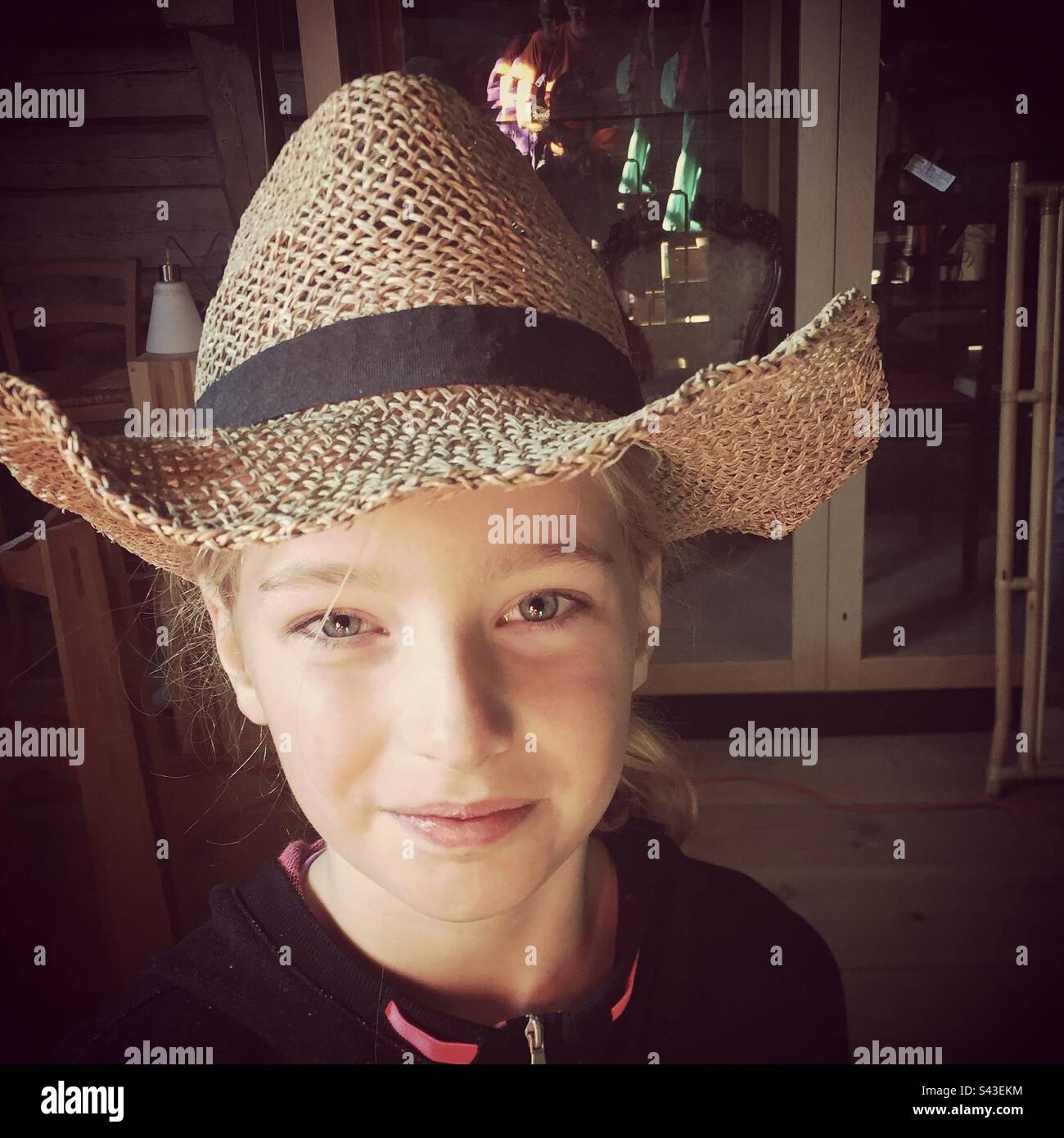 Una giovane ragazza di 10 anni sorridente in un cappello di paglia oversize Foto Stock