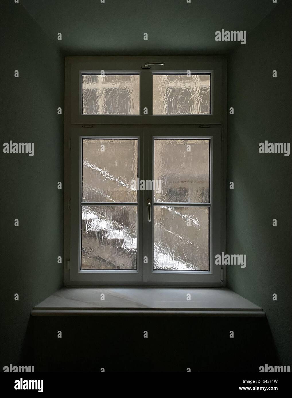 Finestra nel seminterrato di un vecchio hotel austriaco vuoto, vetro appannato e una scala innevata all'esterno. - Immagine stock catturata con smartphone